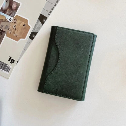 MagSafe leather wallet case in green leather-style finish on a flat surface with magazines.